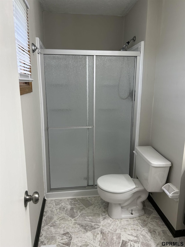 bathroom with baseboards, toilet, and a stall shower