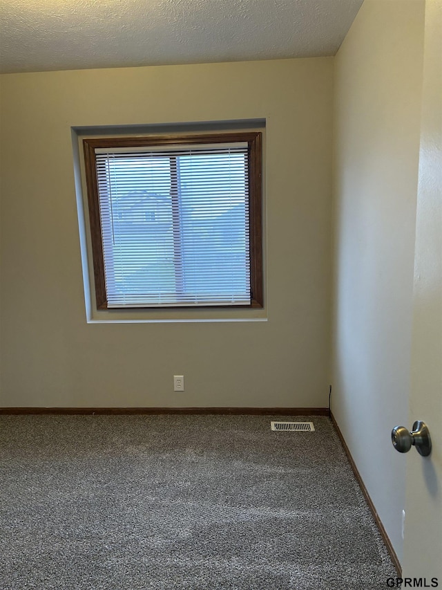 carpeted spare room featuring baseboards and visible vents