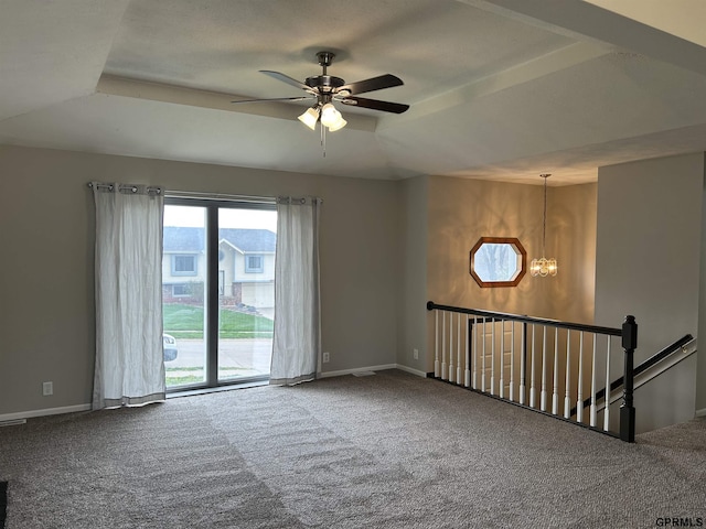 carpeted empty room with baseboards and ceiling fan with notable chandelier