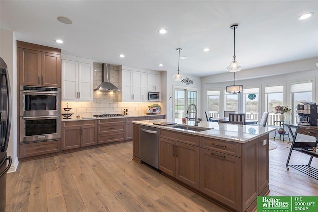 5850 Country Squire Plz, Omaha, NE 68152 - kitchen featuring a sink, wall chimney exhaust hood, stainless steel appliances, light wood-type flooring, and decorative backsplash