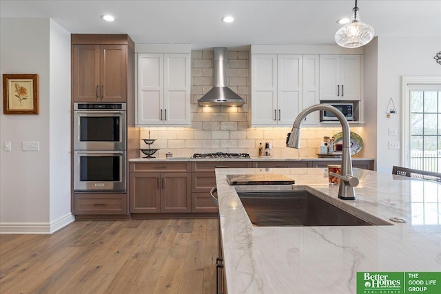 5850 Country Squire Plz, Omaha, NE 68152 - kitchen with stainless steel appliances, wall chimney exhaust hood, a sink, light wood-type flooring, and tasteful backsplash