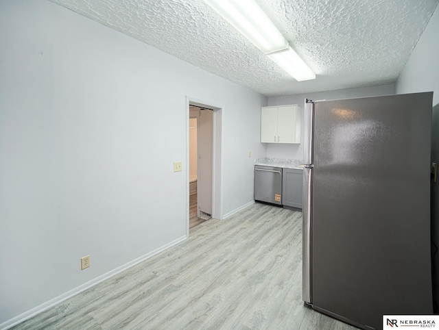 1029 Rose St, Lincoln, NE 68502 - kitchen with stainless steel appliances, light wood-type flooring, a textured ceiling, baseboards, and white cabinets