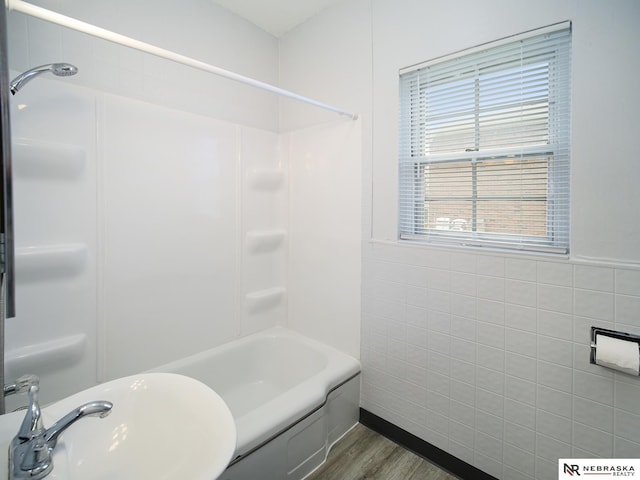 1029 Rose St, Lincoln, NE 68502 - full bathroom featuring a sink, wood finished floors, tile walls, and shower / bath combination