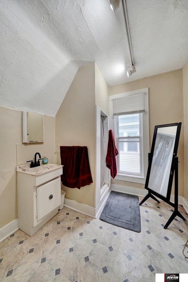 2103 A St, Lincoln, NE 68502 - full bath with a textured ceiling, a shower stall, vanity, baseboards, and lofted ceiling