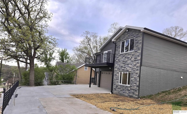 view of side of home with concrete driveway, an attached garage, and stone siding