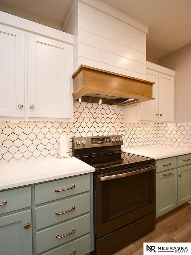 kitchen with light countertops, white cabinets, range with electric cooktop, and decorative backsplash