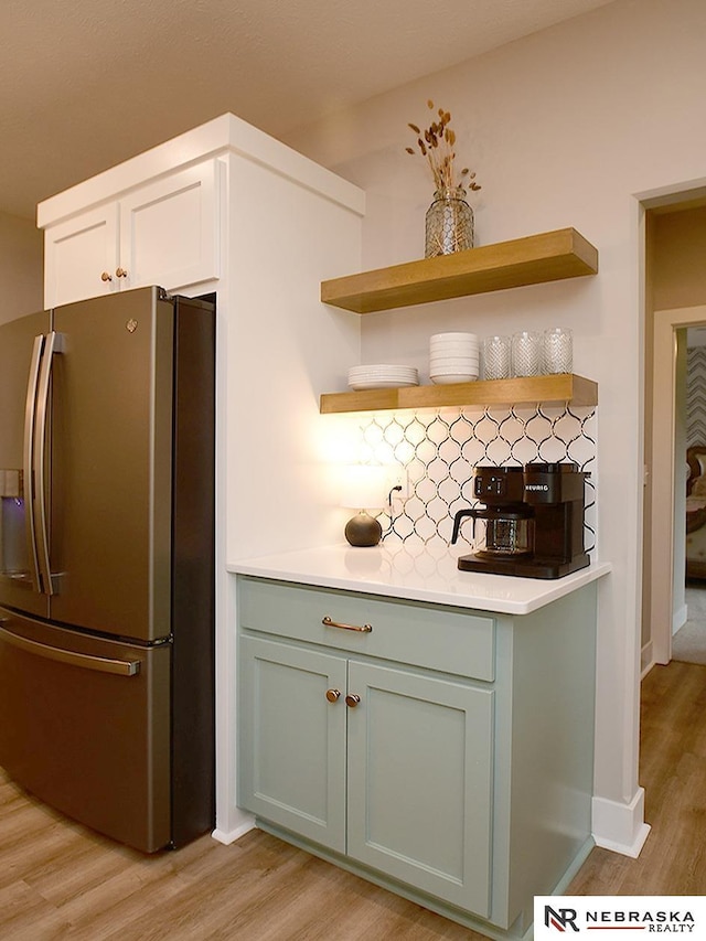 interior space featuring open shelves, light wood-style floors, light countertops, decorative backsplash, and stainless steel refrigerator with ice dispenser