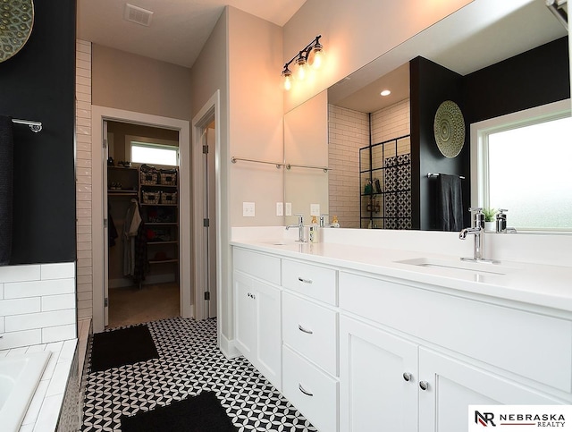 bathroom featuring a sink, a spacious closet, a bath, and visible vents