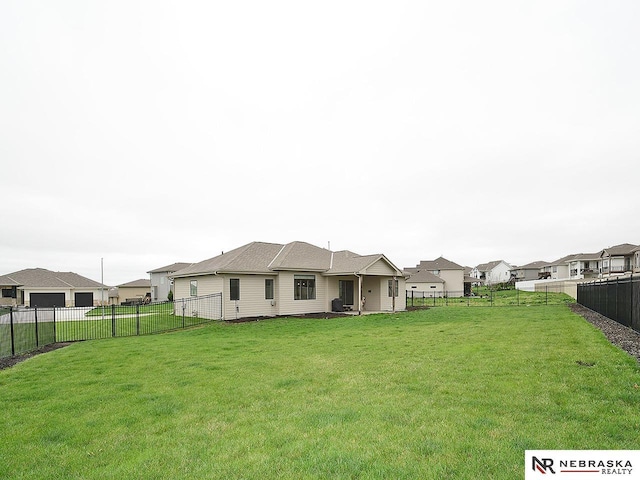 rear view of property with a lawn, a residential view, and a fenced backyard