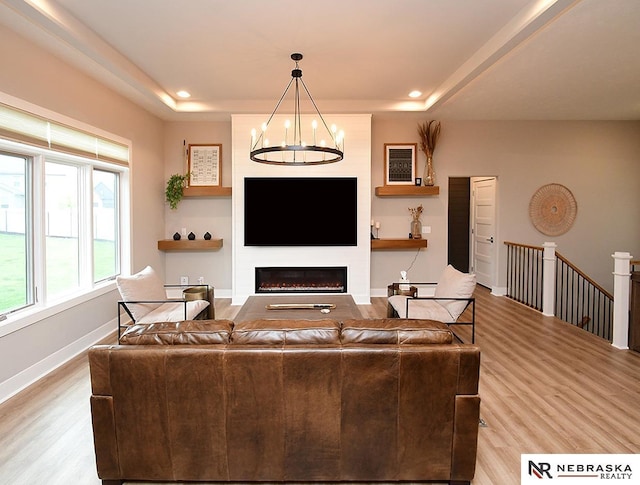 living area featuring recessed lighting, a tray ceiling, a chandelier, and wood finished floors