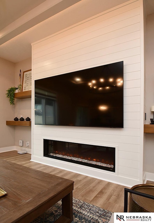 room details with baseboards, a glass covered fireplace, and wood finished floors