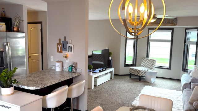 living room with an inviting chandelier, baseboards, and carpet flooring