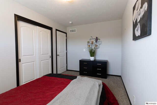 carpeted bedroom featuring baseboards, a closet, and visible vents