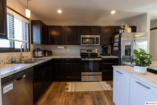 kitchen with dark brown cabinetry, a sink, light countertops, stainless steel appliances, and dark wood-type flooring