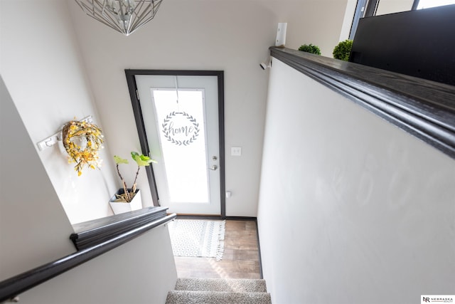 foyer with baseboards, a chandelier, and wood finished floors