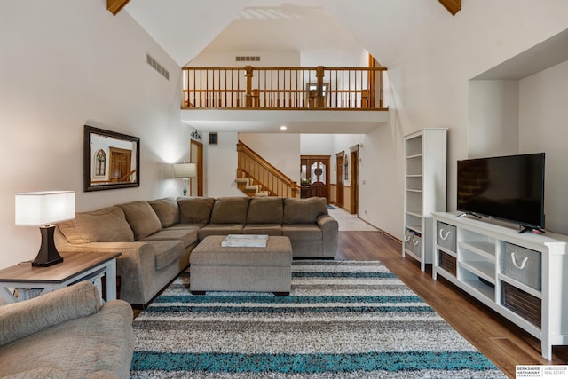 living room featuring stairs, high vaulted ceiling, visible vents, and dark wood finished floors