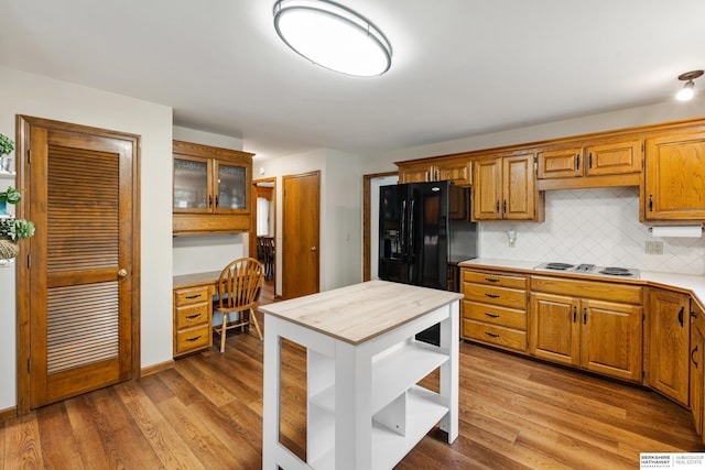 kitchen with built in study area, light wood-style floors, light countertops, white electric cooktop, and decorative backsplash