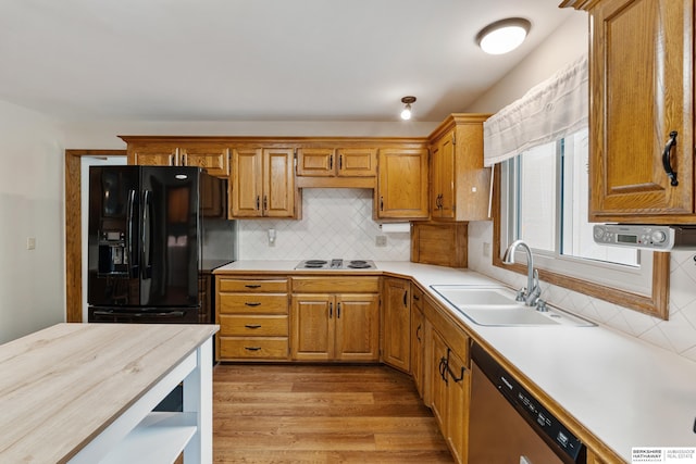 kitchen featuring light countertops, a sink, black refrigerator with ice dispenser, and dishwasher