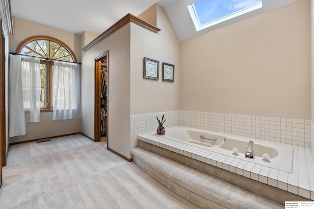 full bathroom featuring baseboards, visible vents, vaulted ceiling with skylight, and a garden tub
