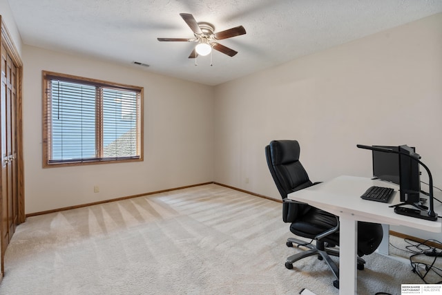office featuring baseboards, ceiling fan, light carpet, and visible vents