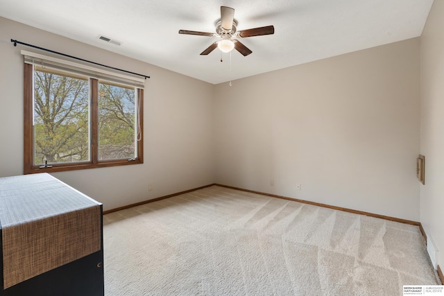 spare room featuring baseboards, a ceiling fan, light colored carpet, and visible vents