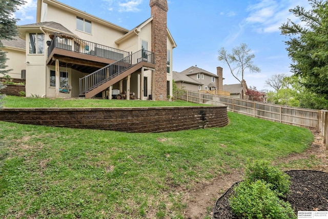 back of house featuring fence, a deck, a chimney, a lawn, and stairway