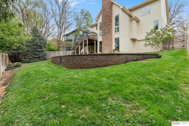 rear view of property featuring a fenced backyard, a yard, a chimney, and a deck