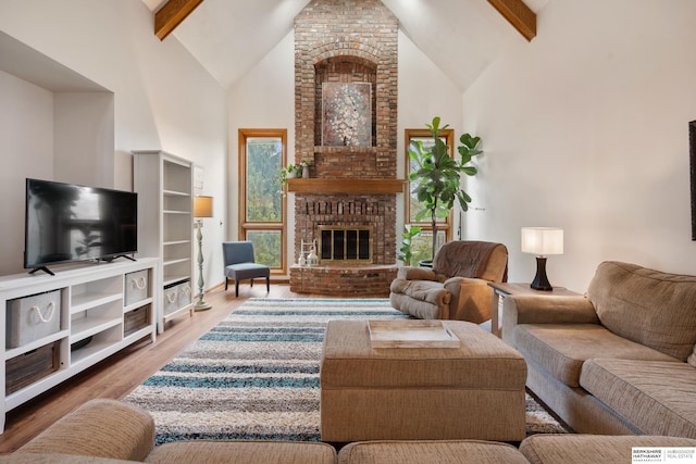 living area with a fireplace, wood finished floors, high vaulted ceiling, and beamed ceiling