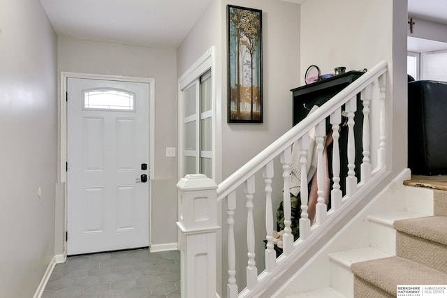 entrance foyer with stairs, light tile patterned flooring, and baseboards