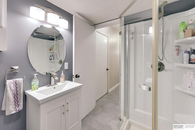 bathroom featuring tile patterned flooring, a textured ceiling, a stall shower, and vanity