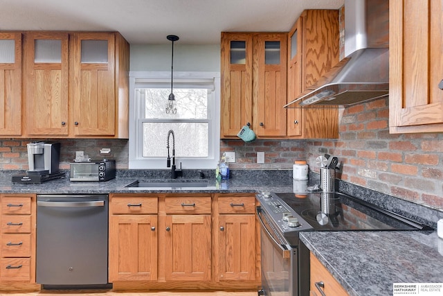 kitchen featuring wall chimney range hood, a sink, dark stone counters, stainless steel dishwasher, and range with electric stovetop