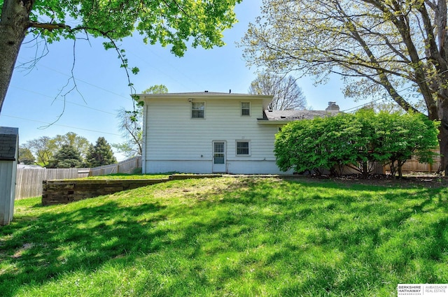 rear view of property with a lawn, fence, and a chimney