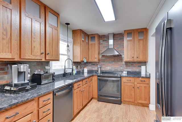 kitchen featuring light wood-style floors, wall chimney range hood, tasteful backsplash, a sink, and stainless steel appliances