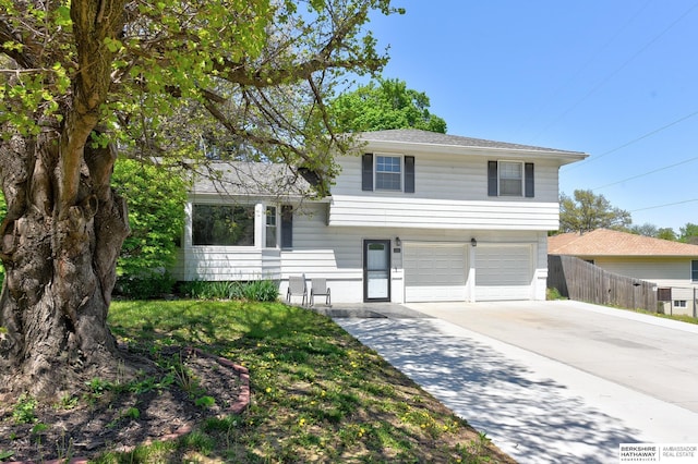 split level home with fence, an attached garage, and concrete driveway