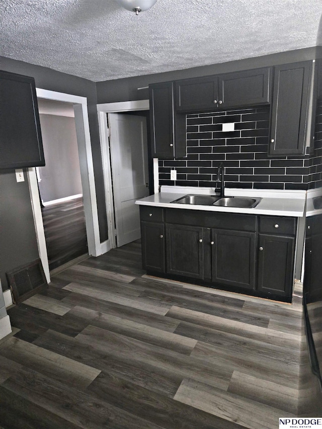 kitchen featuring backsplash, baseboards, a sink, and dark wood-style floors