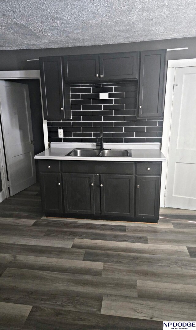 kitchen with backsplash, dark wood finished floors, a textured ceiling, and a sink