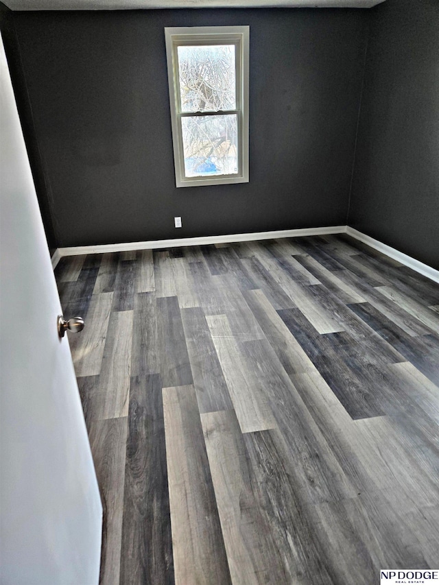 unfurnished room featuring baseboards and wood finished floors