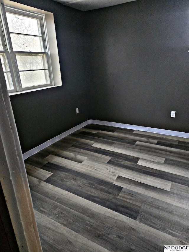 empty room featuring baseboards and dark wood-style flooring