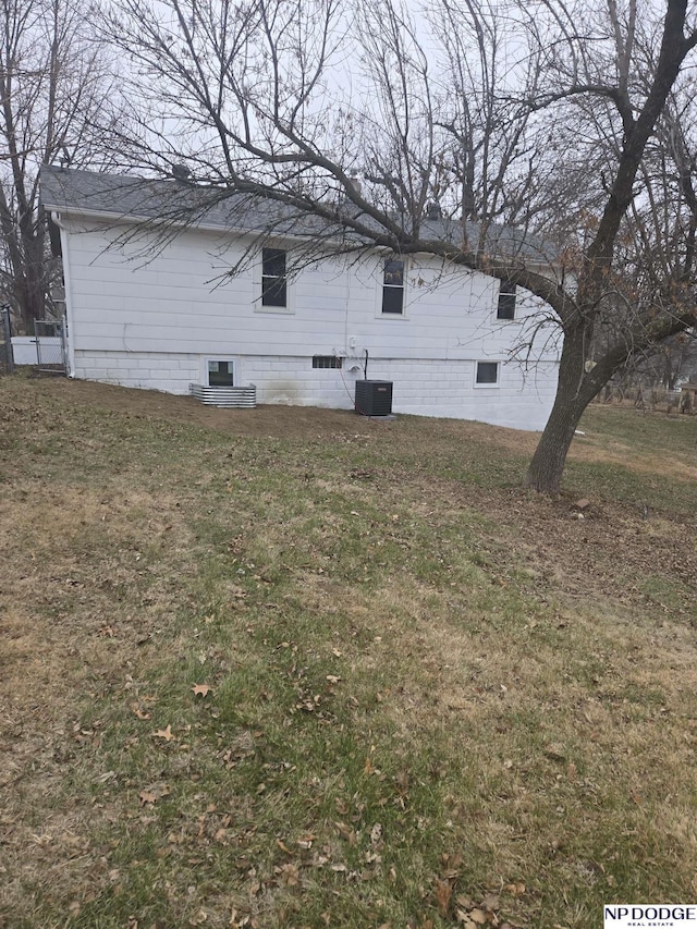 view of side of property featuring central AC unit and a yard