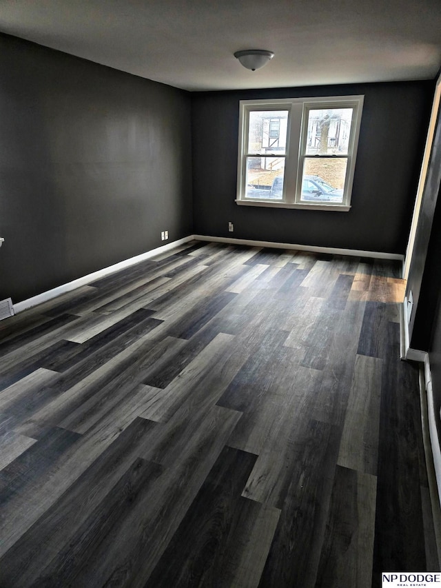 empty room featuring baseboards and dark wood-style floors