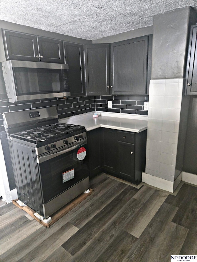 kitchen featuring light countertops, dark wood finished floors, backsplash, and stainless steel appliances