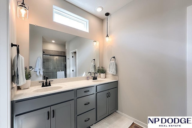 bathroom featuring baseboards, a sink, double vanity, and a stall shower