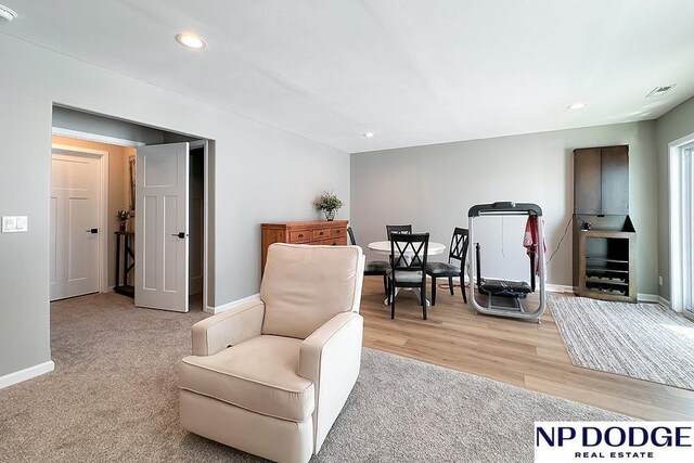 living area with baseboards, visible vents, light wood-type flooring, and recessed lighting