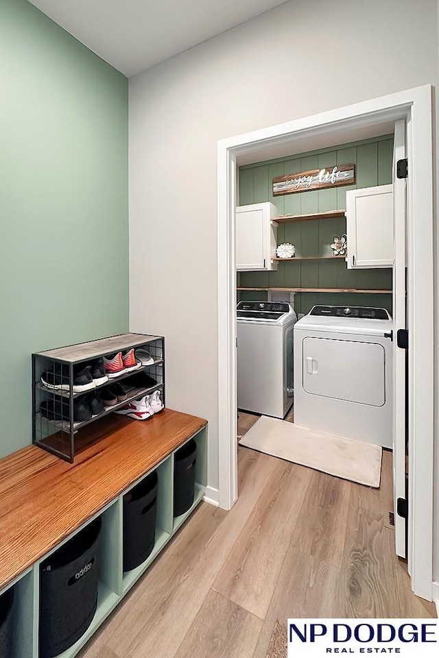 laundry area featuring separate washer and dryer, cabinet space, and wood finished floors