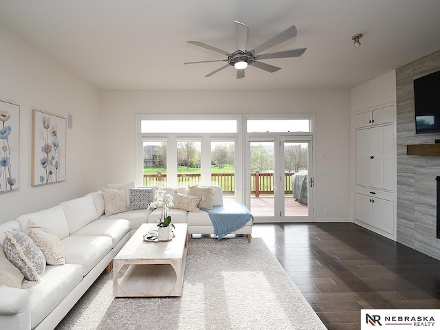 living room featuring a tile fireplace, a wealth of natural light, a ceiling fan, and dark wood-type flooring