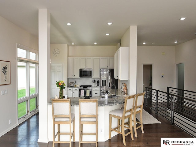 kitchen with light stone counters, a sink, appliances with stainless steel finishes, and a healthy amount of sunlight