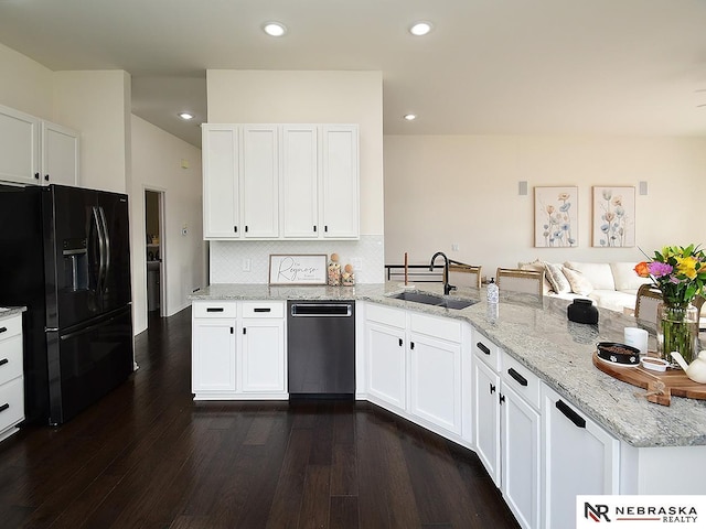 kitchen featuring a peninsula, a sink, black fridge, light stone counters, and dishwasher