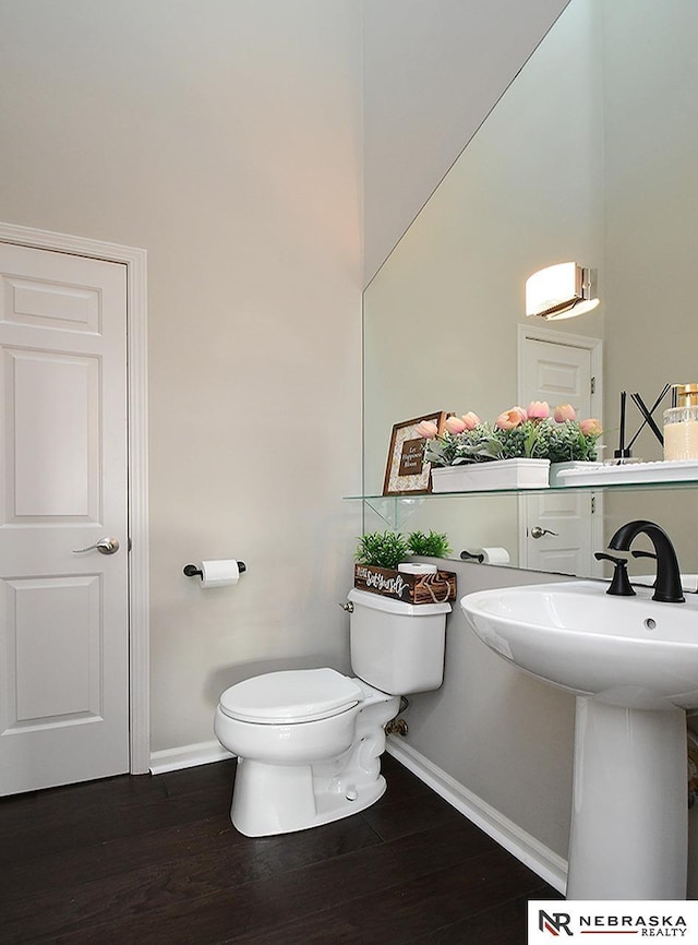 bathroom with wood finished floors, toilet, baseboards, and a sink