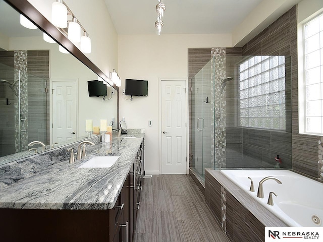 full bath with a bath, a sink, a shower stall, and a healthy amount of sunlight
