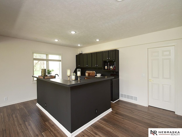 kitchen featuring dark countertops, a textured ceiling, and dark wood-type flooring